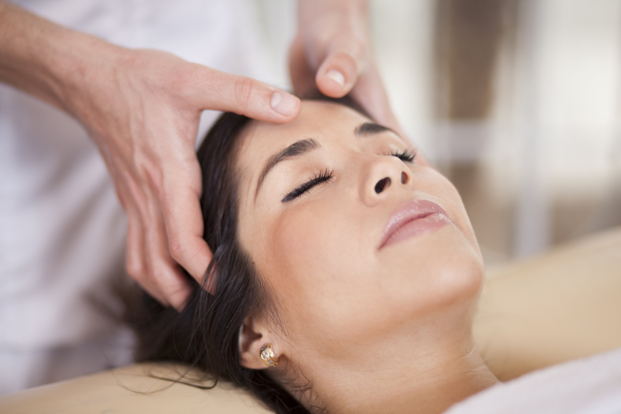 Woman reclines at the salon to receive a scalp massage treatment from stylist.